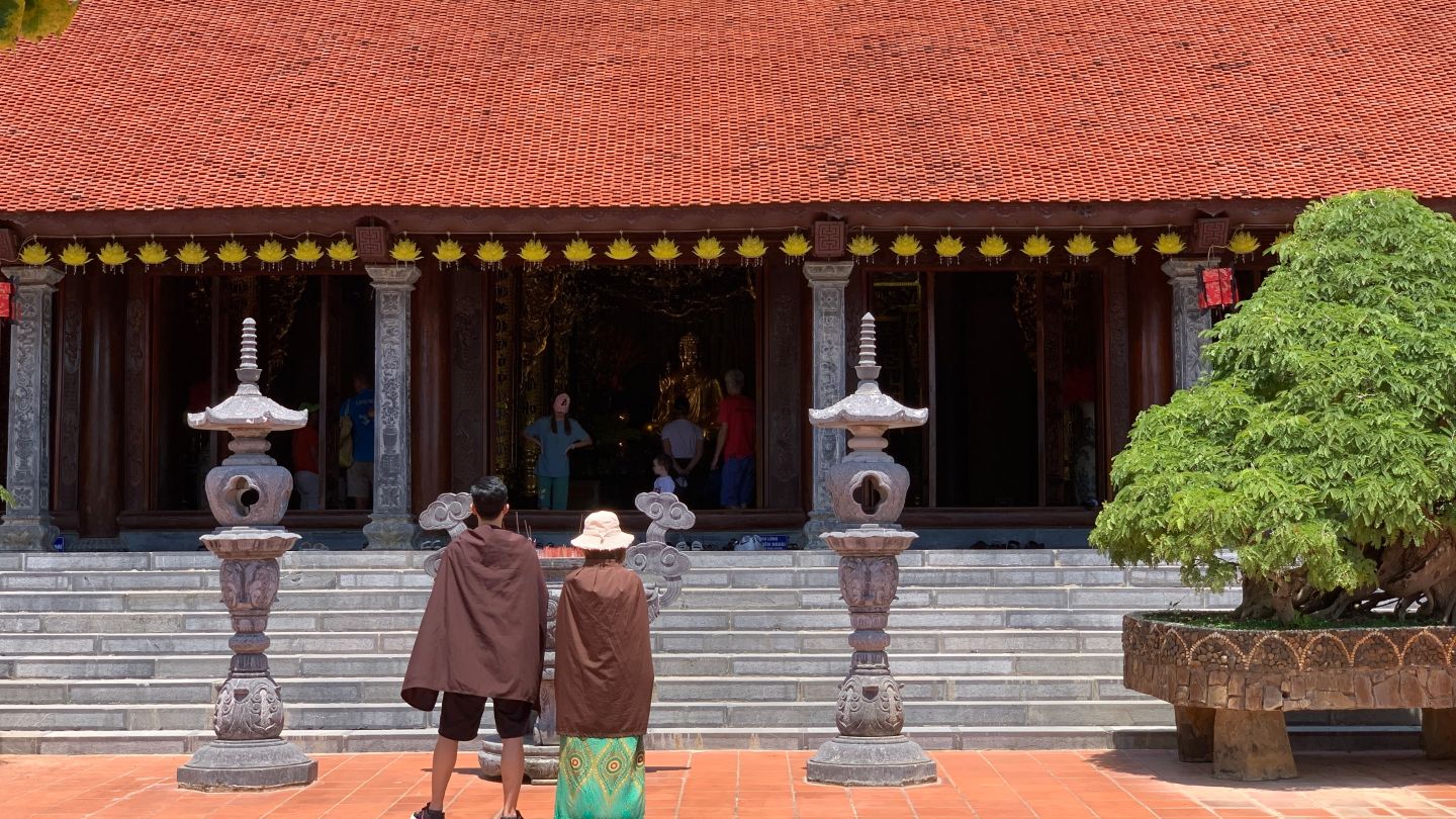 A tourist couple praying outside of main hall Phu Quoc Pagoda